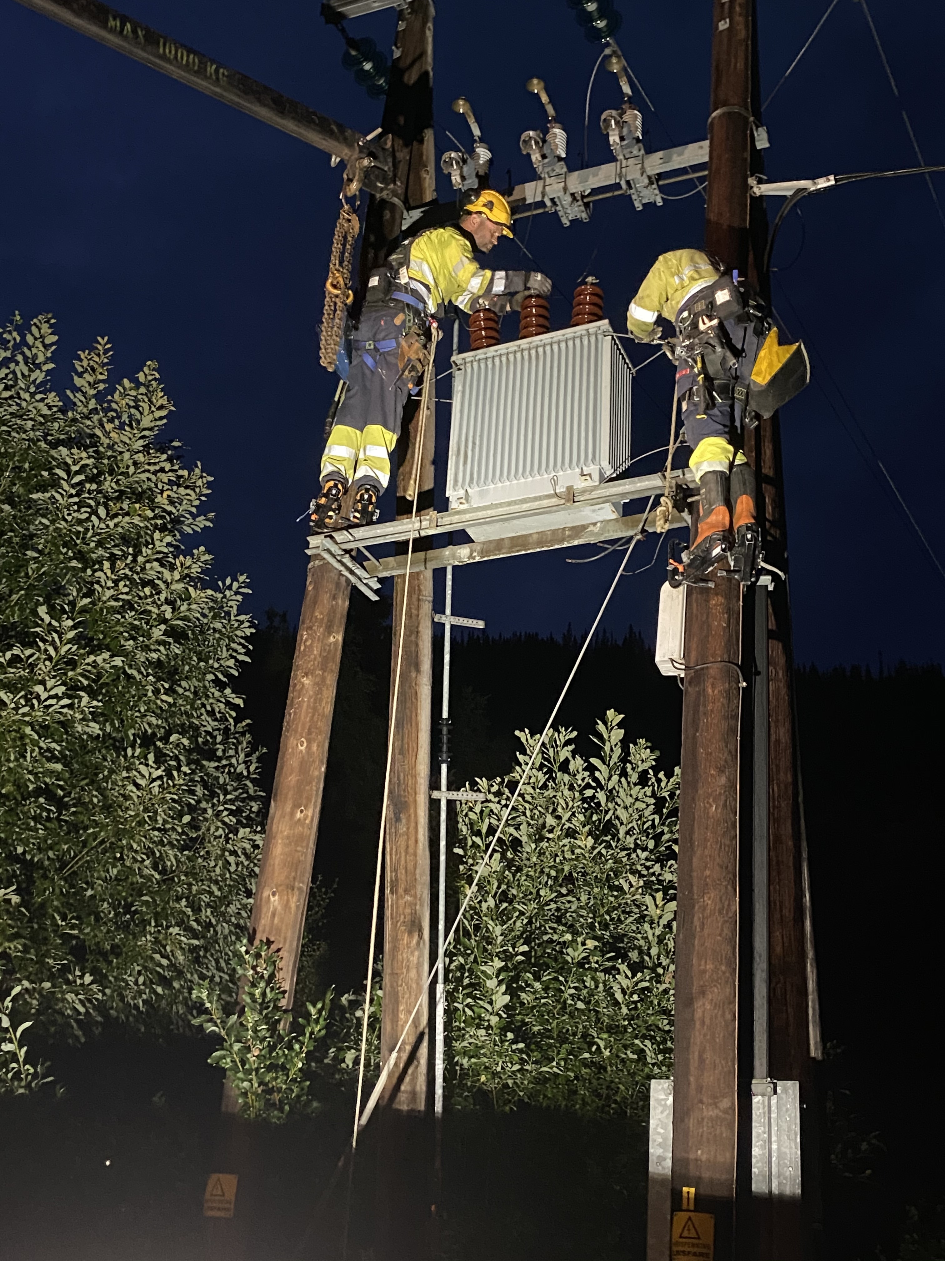 To høystrøm elektriker jobber på en strømnett linje stolpe i kveldshimmel